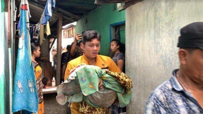 Seorang warga menggendong bayi berusia satu bulan yang tewas di dalam rumahnya
