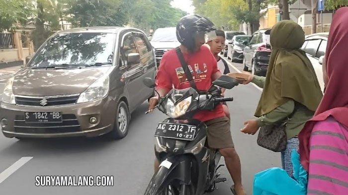 Keluarga Suyatno, terdakwa maling ayam jago milik Kepala Desa Pandantoyo, Kecamatan Temayang, membagikan kotak nasi ayam geprek kepada pengendara yang melintas di Lapas Kelas IIA Bojonegoro, Rabu (7/2/2024) sore.