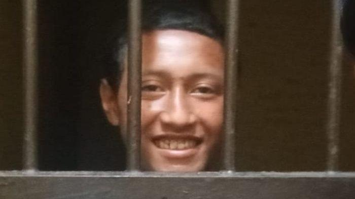 Erus (23) tersenyum dari balik jeruji usai diamankan pihak Polsek Cibalong setelah memutilasi korban sesama ODGJ di Jalan Raya Cibalong, Kampung Bantar Limus, Desa Sancang, Kecamatan Cibalong, Kabupaten Garut, Jawa Barat, Minggu (30/6/2024).