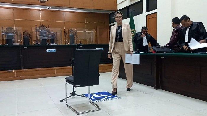 Nikita Mirzani berdiri di depan pengadilan dengan ekspresi serius