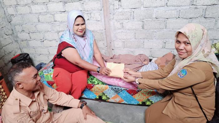 BANTUAN: Bendahara Dinkes Halmahera Selatan, Maluku Utara Lailasari Nurdin (kanan) menyerahkan bantuan uang tunai ke ibu anak pengidap hidrosefalus, Rabu (30/7/2025)