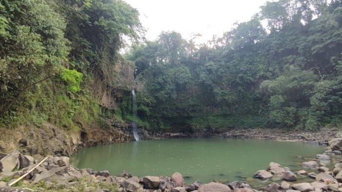 Curug Lontar, tempat wisata air terjun di Bogor berlatar tebing menjulang dengan pepohonan yang merambat di sekitarnya.