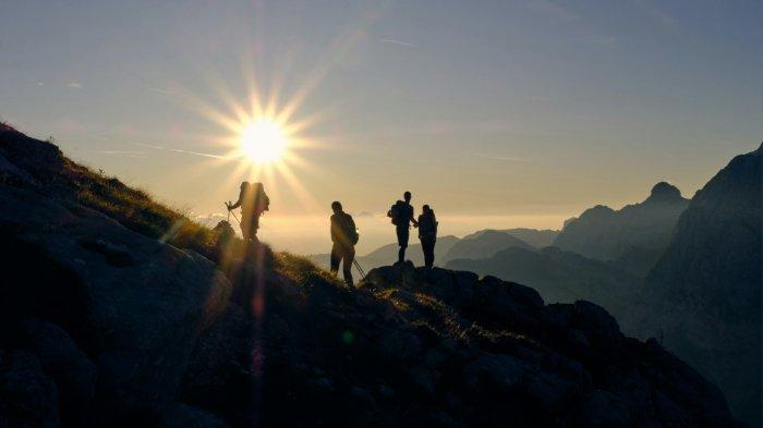 Ilustrasi para pendaki menikmati pemandangan sunrise di gunung.