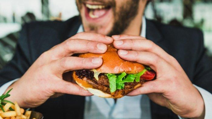 Ilustrasi pria makan burger. Deretan burger di Solo yang terkenal enak.