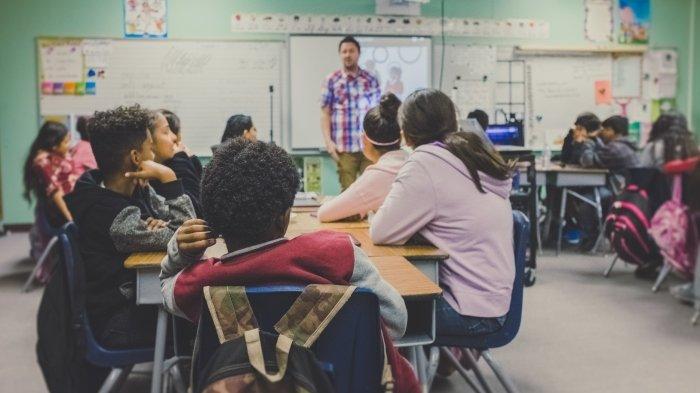 Ilustrasi seorang guru yang sedang mengajar siswa di kelas.