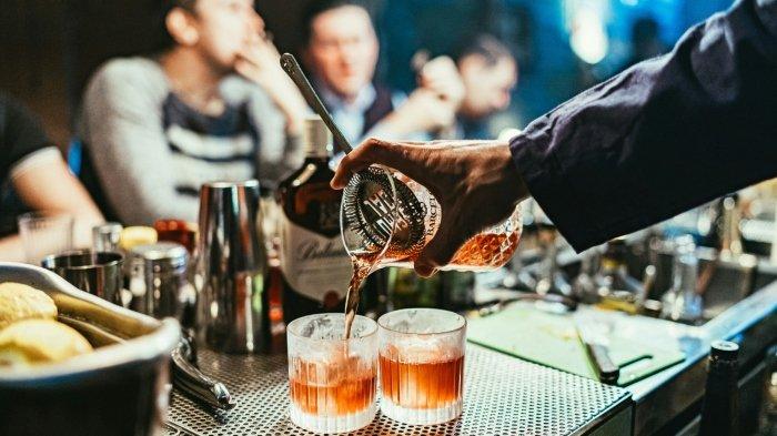 Ilustrasi seorang pria menuangkan alkohol dalam gelas.