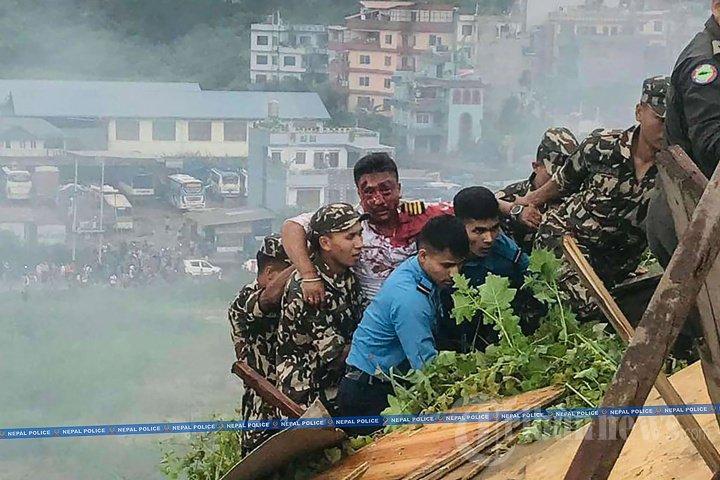 Foto selebaran ini diambil pada tanggal 24 Juli 2024 dan dirilis oleh Kepolisian Nepal menunjukkan tim penyelamat membawa pilot yang terluka (tengah) dari pesawat Saurya Airlines setelah jatuh saat lepas landas di Bandara Internasional Tribhuvan di Kathmandu. - Sebuah pesawat penumpang jatuh saat lepas landas di Kathmandu pada tanggal 24 Juli, dengan pilot diselamatkan dari reruntuhan pesawat yang terbakar tetapi seluruh 18 orang lainnya di dalam pesawat tewas, kata polisi di ibu kota Nepal kepada AFP.