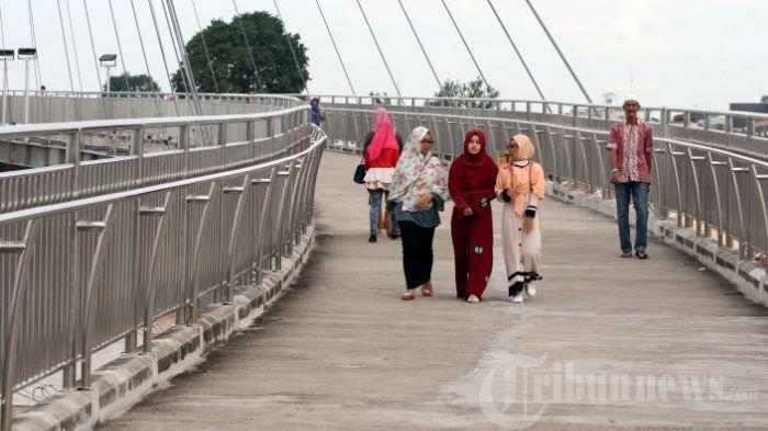 Masyarakat melintasi Jembatan Pedestrian yang menghubungkan Menara Gentala Arasy di atas Sungai Batanghari, Jambi, Selasa (6/6/2017).