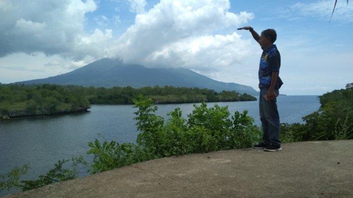 Kepala Desa Baopana Frans Lengari sedang berdiri di lokasi wisata Pantai Batu Payung dengan latar belakang teluk dan Gunung Ile Lewotolok yang masih berselimut awan putih, Kamis (12/3/2020).