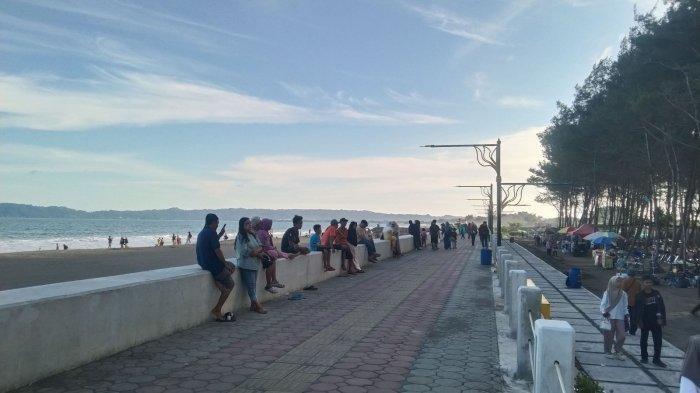 PANTAI KEMIREN - Sejumlah wisatawan saat menikmati suasana liburan di Pantai Kemiren, Cilacap di momen libur Hari Raya Waisak, Senin (12/5/2025) sore. Beberapa wisatawan penasaran dengan desain Pantai Kemiren yang menyerupai Pantai Ancol, Jakarta.