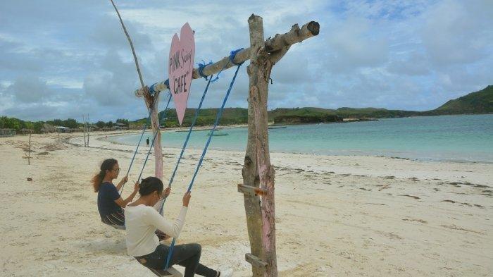 Dua orang wisatawan menikmati Pantai Tanjung Aan dengan bermain ayunan, Jumat (8/1/2021).