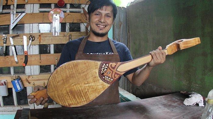 Pengrajin alat musik Gambus Melayu, Robithah Irawan (34) memegang produk gambus andalannya yang dinamakan RD Series.