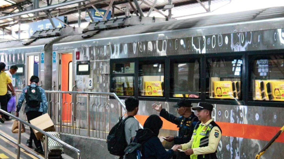 Para petugas di stasiun kereta api yang sedang menunjukkan gerbong kereta kepada penumpang.