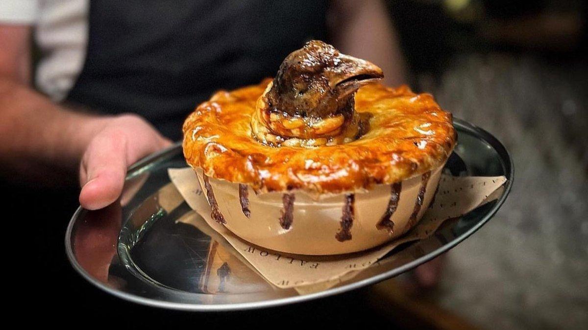 Pie isi kepala ayam menyembul keluar ini disajikan sebuah restoran di Inggris.