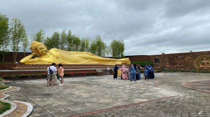 Wisatawan lokal saat berswafoto di Patung Buddha Tidur yang berada di Vihara Dharma Shanti, Bintan, Minggu (24/12/2023). Vihara ini termasuk tujuan wisata religi di Bintan, Kepulauan Riau.