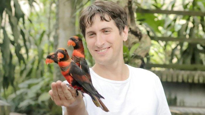 Wisatawan pria berfoto dengan burung di Bali Bird Park, tempat wisata ramah keluarga di Kecamatan Sukawati, Kabupaten Gianyar, Bali.