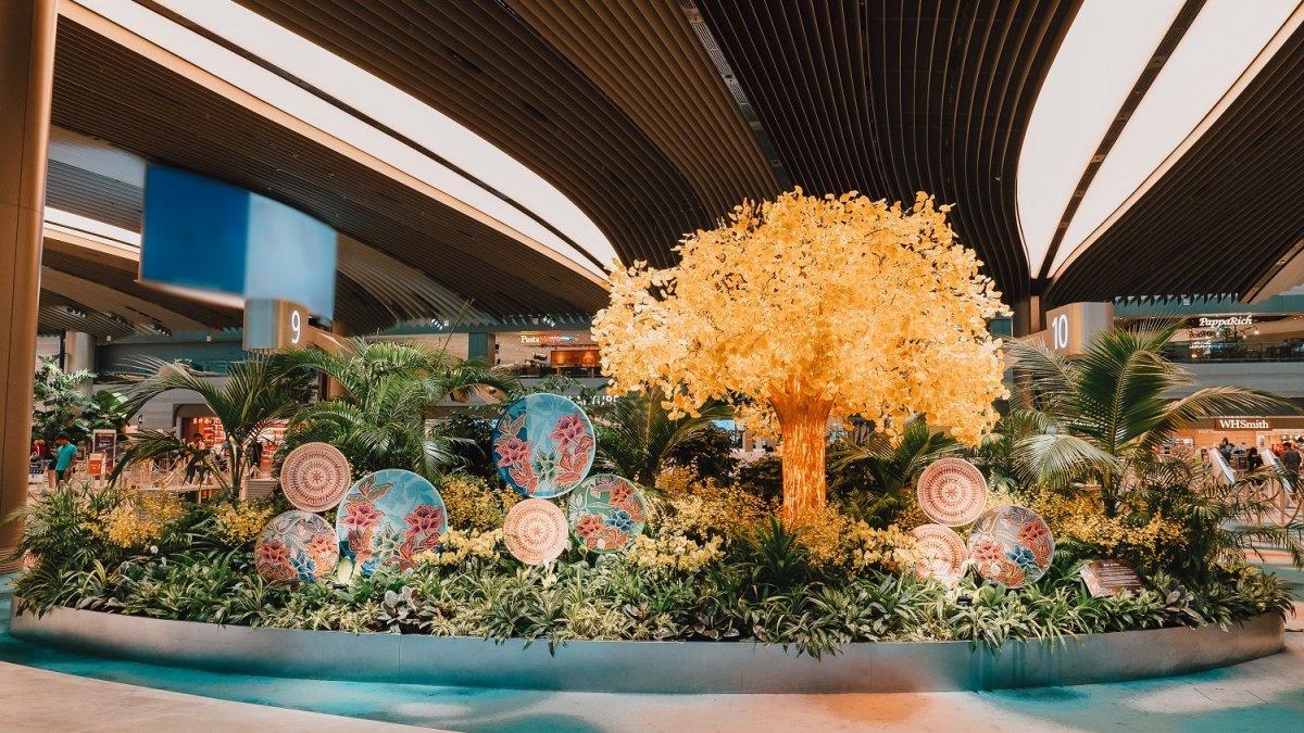 Tempat penyaringan yang semarak dengan desain bunga batik dan patung 'Pohon Kehidupan' Changi di Terminal 2, Changi Airport, Singapura