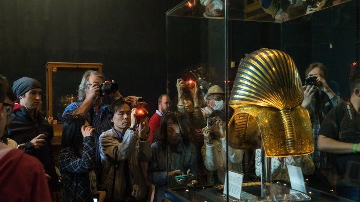 Pengunjung berkerumun untuk mengambil foto topeng pemakaman emas Raja Tutankhamun yang terkenal di Museum Mesir di Kairo, Mesir pada akhir Desember 2015. Topeng itu dilepas dari pajangan pada Oktober 2015 untuk proyek restorasi dan pemeriksaan selama sembilan minggu.