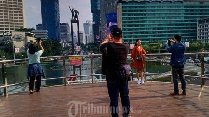 Warga menikmati pemandangan dan foto selfie dari lantai 2 halte Transjakarta Bundaran HI, Jalan MH Thamrin, Jakarta Pusat, Minggu (9/10/2022).