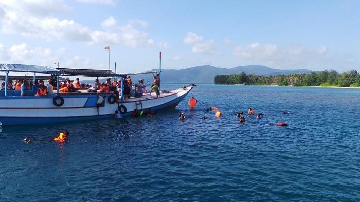 Para wisatawan sedang menikmati Laut Karimunjawa dengan melakukan snorkeling saat mengikuti paket wisata 