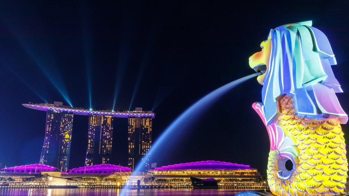 Lampu bersinar di Merlion saat menghadap Marina Bay Sands Singapura yang ikonis.
