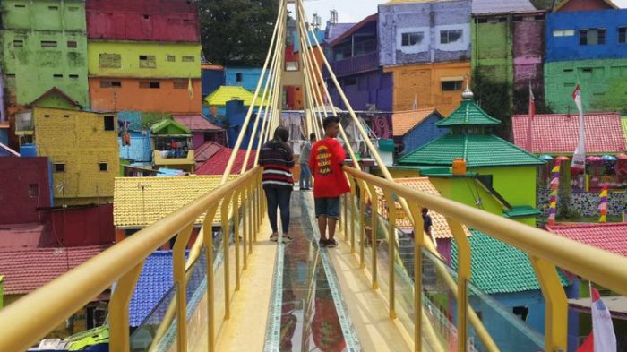 Sejumlah wisatawan saat melintas di jembatan kaca yang menghubungkan Kampung Warna - warni dan Kampung Tridi di Kota Malang, Jawa Timur
