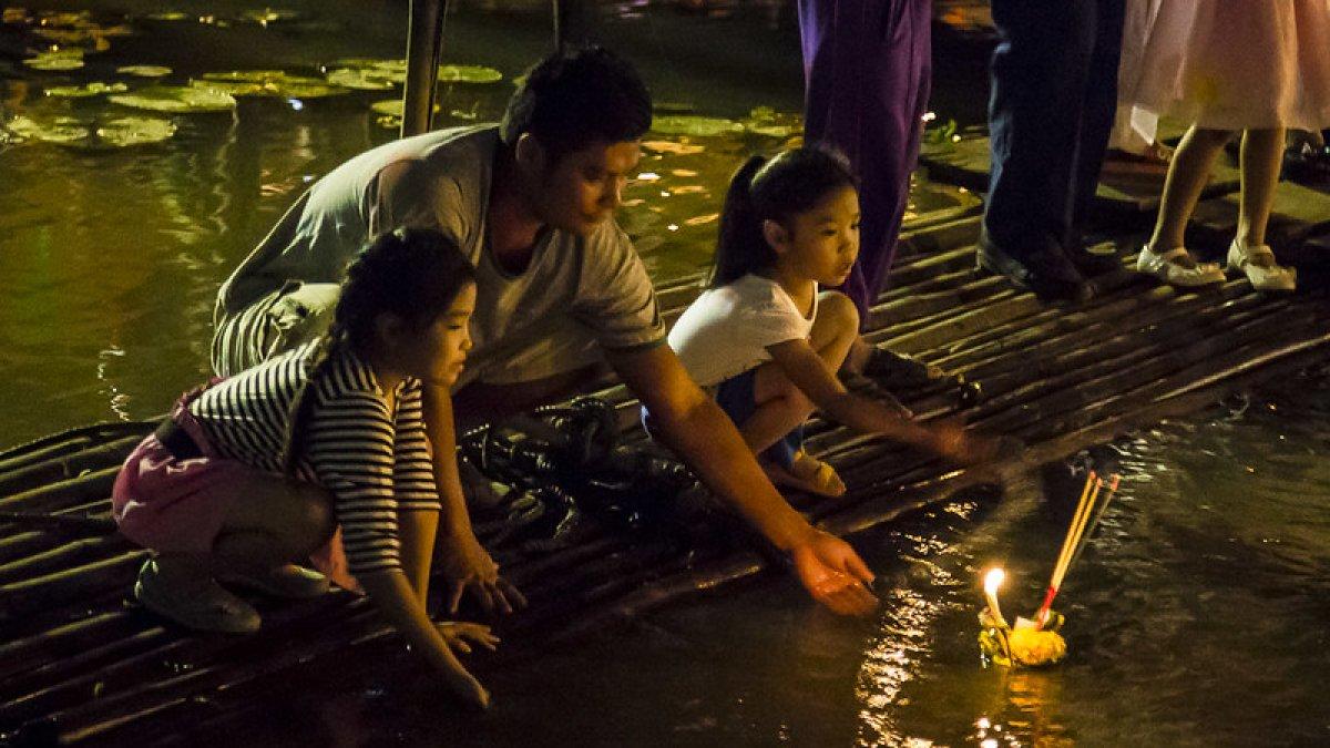 Orang Thailand mengatur krathong yang diterangi lilin di sungai Ping pada malam hari selama Loy Krathong