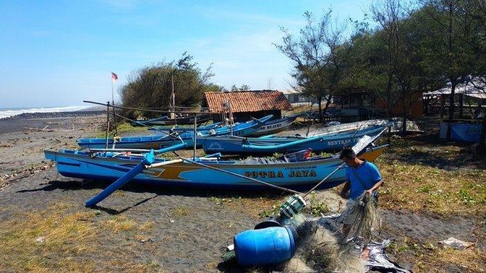 Nelayan Pantai Congot tengah membetulkan jaring dan kapalnya. Gelombang tinggi di laut selatan belakangan ini memaksa mereka urung melaut.
