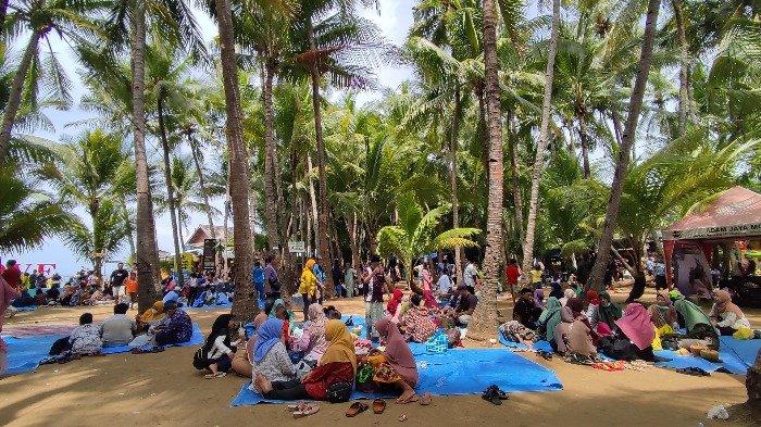 Wisatawan sedang asyik berpiknik bersama keluarga dan kerabat dekat di kawasan Pantai Kelapa, Tuban, Jawa Timur, Minggu (14/11/2021).