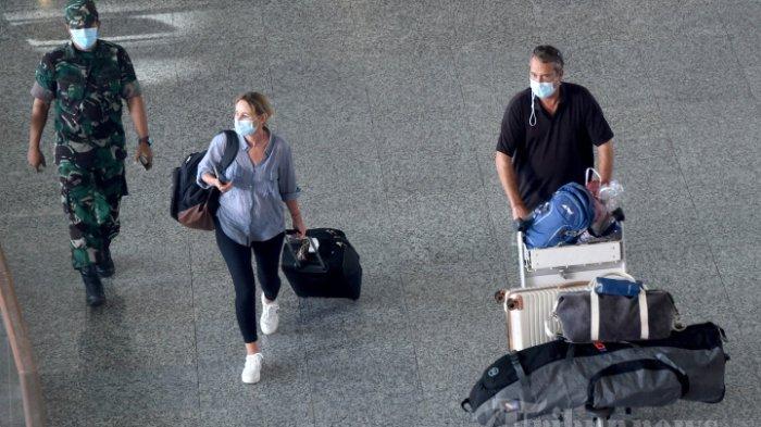 Pelancong berjalan melalui ruang kedatangan internasional di Bandara Internasional Ngurah Rai di Tuban dekat Denpasar Bali pada 16 Februari 2022, setelah penerbangan Singapore Airlines tiba setelah istirahat hampir dua tahun karena Covid-19.