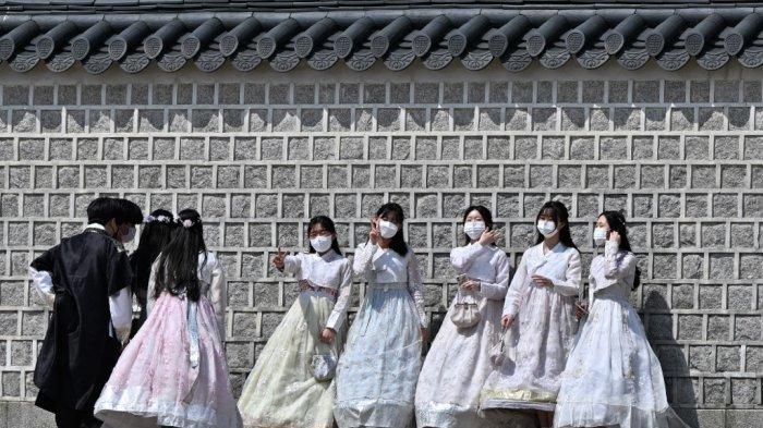 Pengunjung yang mengenakan gaun hanbok tradisional berpose untuk foto di Istana Gyeongbokgung di Seoul pada 2 Mei 2022.
