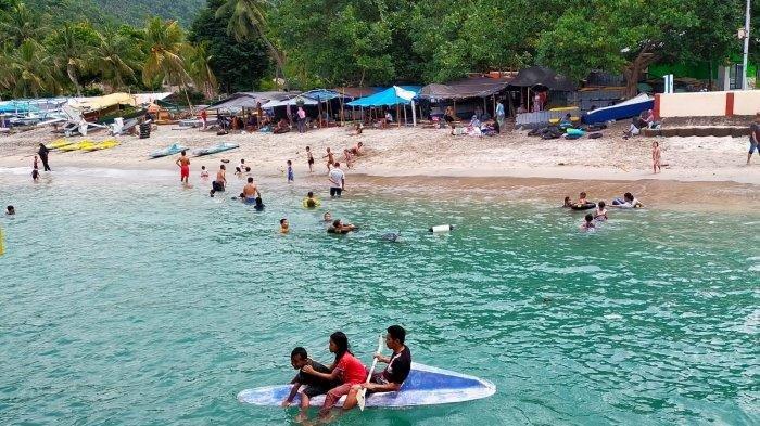 Seorang bapak mengajak dua anaknya menikmati Pantai Senggigi menggunakan kano, di Lombok Barat.