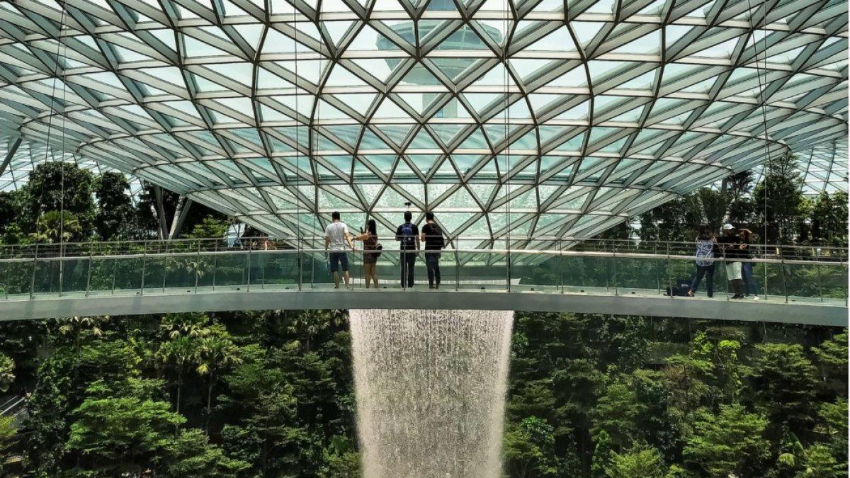 Ilustrasi penumpang pesawat transit yang menghabiskan waktu menyaksikan air terjun dalam ruangan terbesar di dunia yang ada di Jewel, Bandara Changi, Singapura