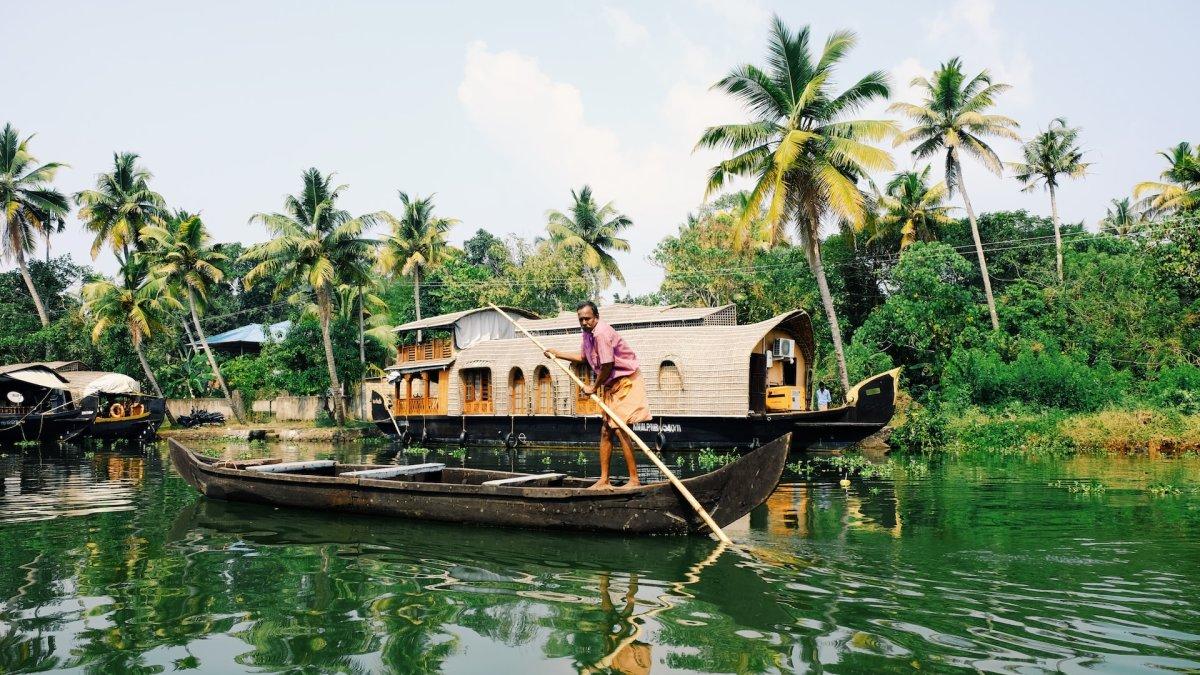 Wisatawan yang sedang berada di atas perahu menyusuri daerah terpencil Kerala India sambil mengamati anak-anak bermain di sungai.