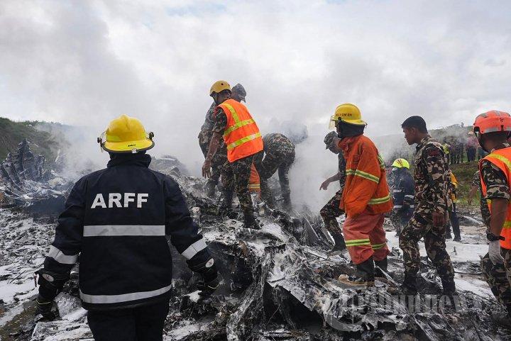 Tim penyelamat dan personel militer berdiri di lokasi setelah pesawat Saurya Airlines jatuh saat lepas landas di Bandara Internasional Tribhuvan di Kathmandu pada 24 Juli 2024. - Sebuah pesawat penumpang jatuh saat lepas landas di Kathmandu pada 24 Juli, dengan pilot diselamatkan dari reruntuhan pesawat yang terbakar tetapi seluruh 18 orang lainnya tewas, kata polisi di ibu kota Nepal kepada AFP.
