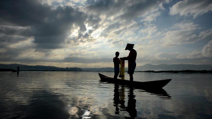 Paidi (48) mengajarkan cara merapikan jala kepada Rizal (12), keponakannya, di Rawa Pening, Desa Asinan, Kecamatan Bawen, Kabupaten Semarang, Jawa Tengah, Jumat (26/6).