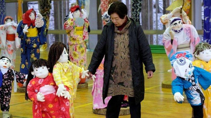 Tsukimi Ayano memeriksa boneka seukuran yang dipajang di sebuah sekolah dasar, yang ditutup tujuh tahun lalu karena tidak ada yang tersisa untuk mengajar, di desa kecil Nagoro di Jepang barat.