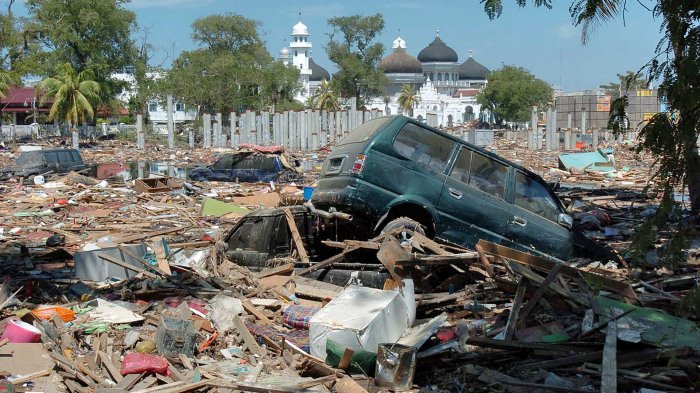 Sebuah mobil Kijang yang terpelanting akibat gempa dan gelombang tsunami berada di antara puing-puing bangunan
