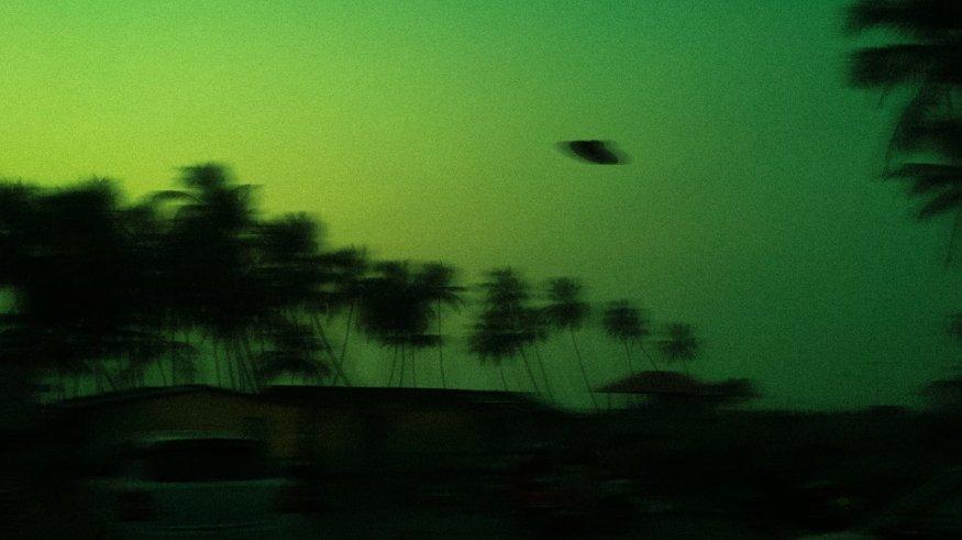 Ilustrasi ufo terbang melintasi kota.