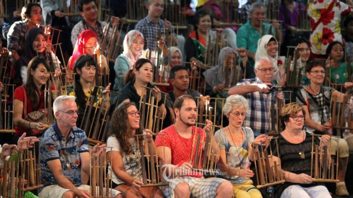 Wisatawan asing dan lokal bersama-sama memainkan alat musik tradisional Jawa Barat angklung pada acara 'Angklung Pride 6', di Saung Angklung Udjo, Jalan Padasuka, Kota Bandung, Jawa Barat