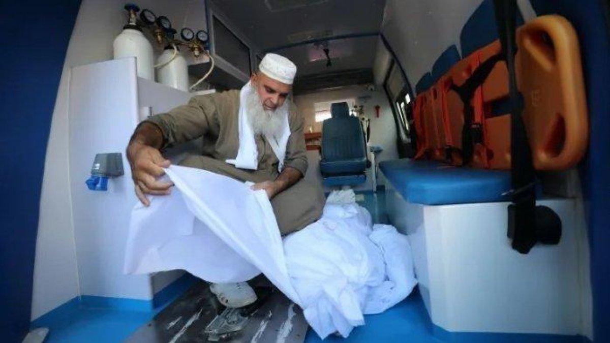 Abu Saher al-Maghari membungkus jenazah korban serangan Israel yang tiba di Rumah Sakit Martir Al-Aqsa di Deir el-Balah.