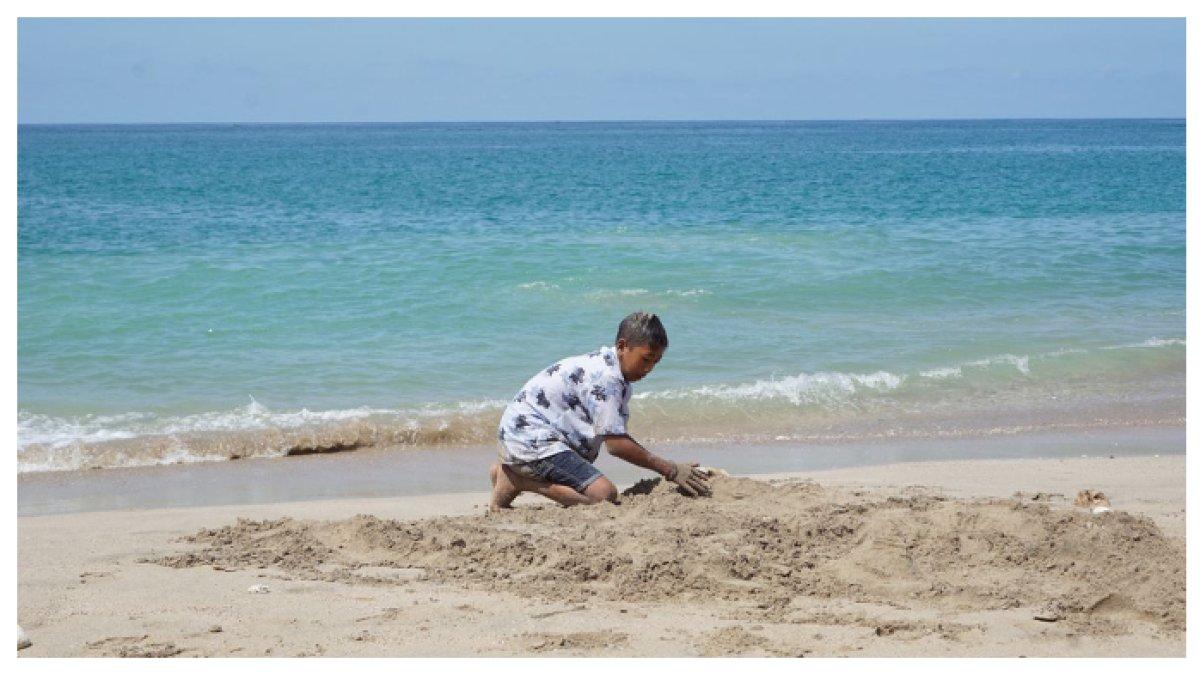 BERMAIN PASIR di PANTAI TAMBAKREJO - Anak-anak dan wisatawan sedang asyik bermain pasir di Pantai Tambakrejo, menikmati suasana santai dengan pemandangan alam yang menenangkan.