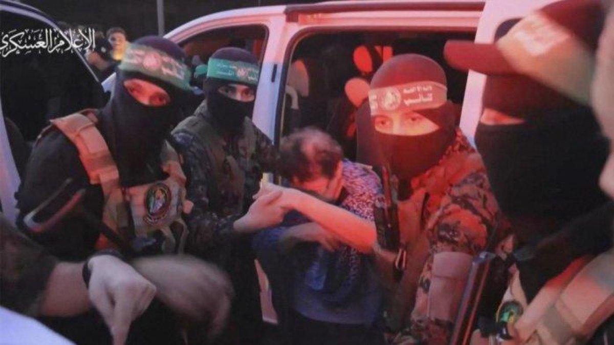 Seorang anggota Brigade Al-Qassam membantu seorang sandera keluar dari mobil sebelum menyerahkannya kepada pejabat dari Komite Internasional Palang Merah di Gaza pada 24 November 2023.