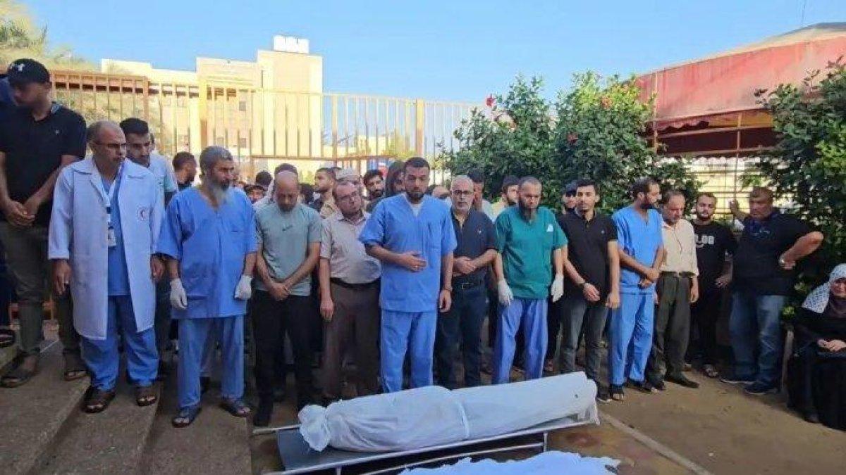 Iyad Shaqura (tengah) dokter di Rumah Sakit Nasser di Gaza, memimpin sholat jenazah pada Selasa (7/11/2023) untuk delapan anggota keluarganya yang meninggal dunia setelah terkena serangan Israel di kamp pengungsi Khan Yunis, Gaza, pada Senin (6/11/2023). Iyad Shaqura yang merupakan kepala Departemen di Rumah Sakit Medis Nasser sedang bertugas ketika dia menerima kabar duka tersebut.