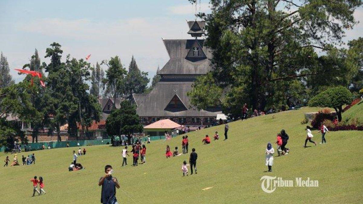 Sejumlah pengunjung menikmati suasana padang rumput hijau di Bukit Kubu, Brastagi, Sumatera Utara, Minggu (5/8/2019).