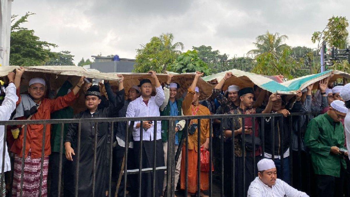 Para pelayat Habib Hasan bin Ja'far Assegaf yang berlindung dari hujan menggunakan alas terpal di luar Masjid Nurul Musthofa Center, Cilodong, Depok, Kamis (14/3/2024).