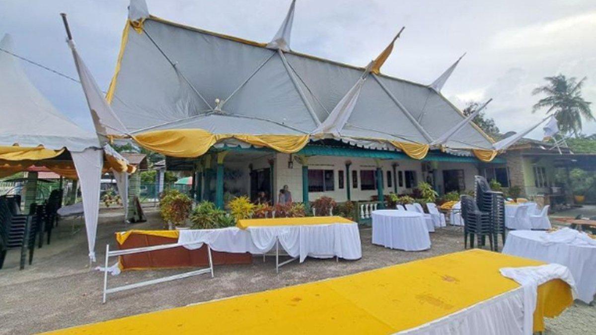 Tenda hajatan nyangkut di atap rumah karena diterpa angin kencang.