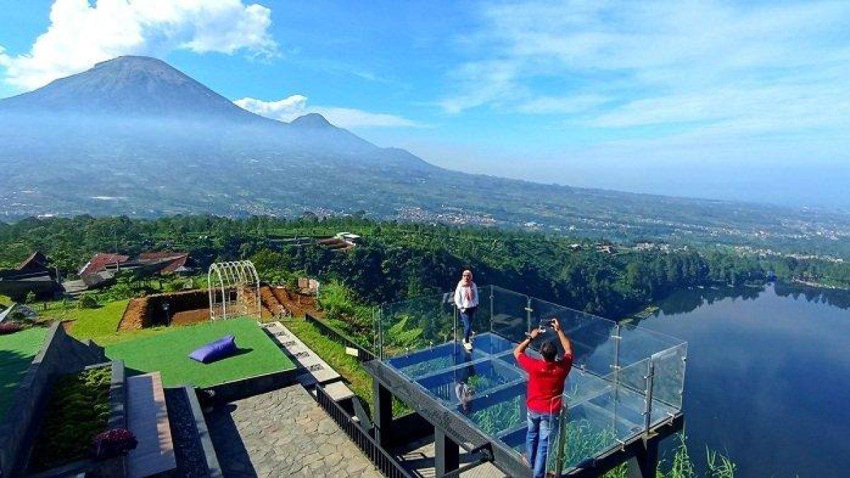 Pengunjung berfoto di jembatan kaca Kahyangan Skyline Wonosobo, Sabtu (17/6/2023). Tempat wisata ini menawarkan pemandangan keindahan alam Telaga Menjer, Gunung Sindoro, dan Gunung Sumbing.