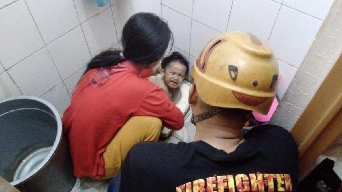 Petugas Damkar saat melepaskan tangan bocah yang tersangkut di dalam toilet