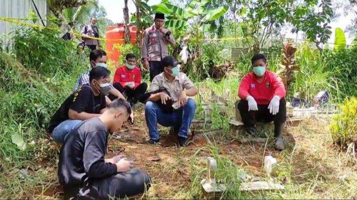 Polisi berjaga saat proses pembongkaran makam remaja MR (14) di Pacitan, Jumat (12/1/2023). MR diduga meninggal karena minum kopi beracun.